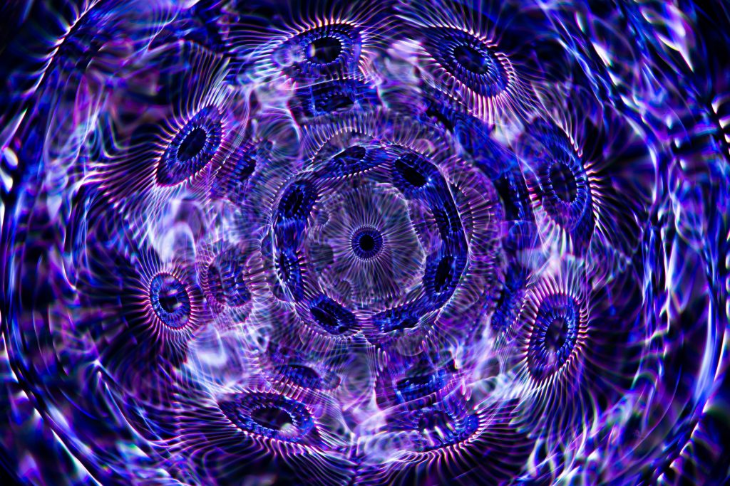 A dynamic, colorful abstract pattern with geometric and kaleidoscope effects in vibrant purples and blues.