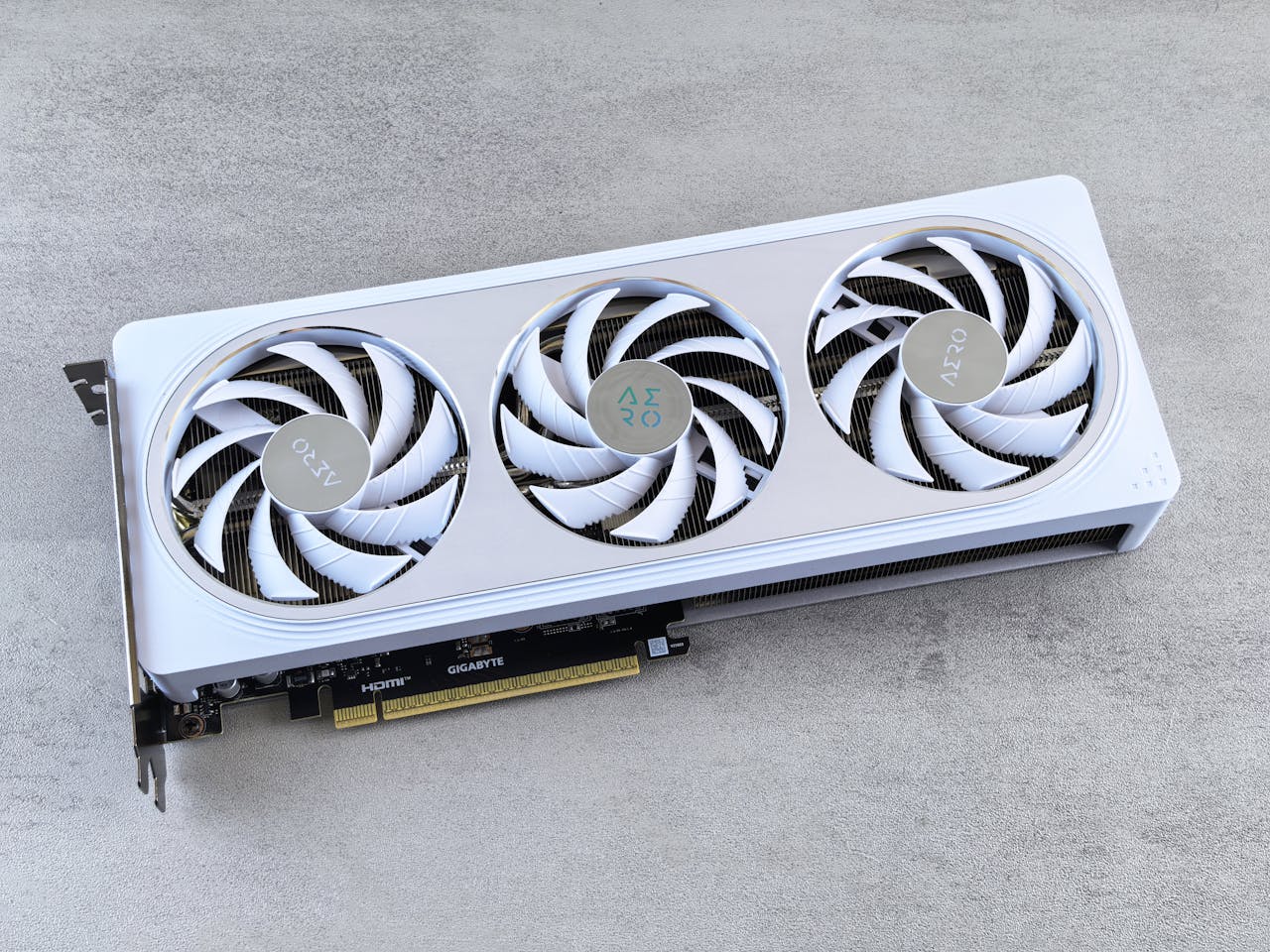 Stylish white graphics card with three cooling fans on a neutral background, ideal for tech enthusiasts.